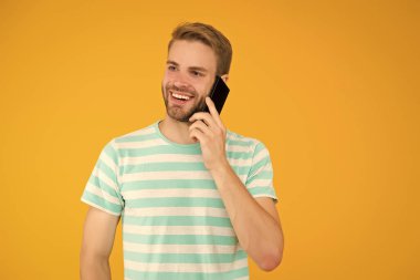 İletişim kurmanın önemini. Cep telefonunun sarı arka planında mutlu adam konuşması. Sözlü iletişim. Mobil iletişim. Telefon iletişimi. İletişim teknolojisi. Modern hayat