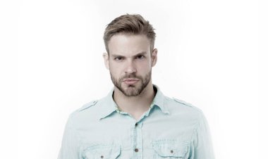 Ciddi yüzlü sakallı bir adam beyaz arka planda izole edilmiş. Mavi gömlekli yakışıklı adam, moda. Sakallı ve şık. Kuaför ve berber salonu. Cilt bakımı ve bakım. Sıradan bir tarz.