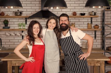 Pazar geleneğimiz. Nefis bir kahvaltı hazırla. Öğle yemeği vakti. Aile birlikte yemek yaparken eğleniyor. Çocuklara yemek yapmayı öğret. Birlikte yemek pişirmek. Anne, baba ve kız önlükleri mutfakta. Yemek pişirme konsepti