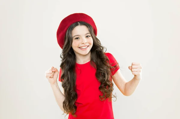 Glücklich und schön. Kleine Mädchen mit langen gesunden, glänzenden Haaren tragen einen roten Hut. Kleines Mädchen mit langen Haaren. Kind glücklich niedliches Gesicht liebenswert lockiges Haar gelb Hintergrund. Beauty-Tipps für gepflegtes Haar. Lächelndes Kind — Stockfoto