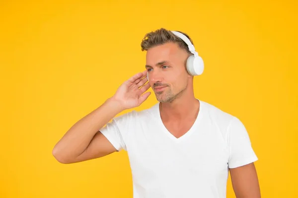 Homem caucasiano de meia-idade grave ouvir música tocando em fones de ouvido modernos em estilo casual fundo amarelo, som, espaço de cópia — Fotografia de Stock