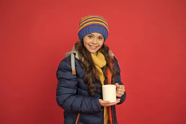 Čas na energii. Šťastné dítě si vychutnat horký nápoj v zimní den. Malá dívka držet čaj nebo kakao pohár červené pozadí. Horký nápoj. Zvýšení energie. Zvyšování energie v ranních hodinách — Stock fotografie