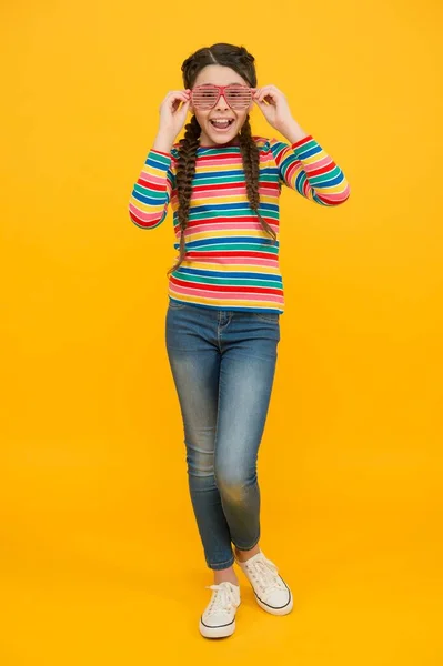 Menina adolescente feliz com cabelo trançado usar estilo casual cor do arco-íris e óculos de festa glamour no fundo amarelo, otimista — Fotografia de Stock