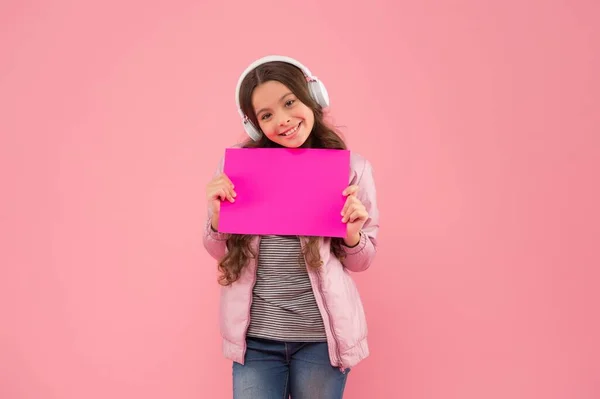 Glad tonåring flicka lyssna musik i hörlurar presentera tomt papper, teknik — Stockfoto
