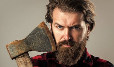 Adam elinde bir balta tutuyor. Baltası olan sakallı bir oduncu. Ekose gömlekli bir oduncu. Oduncu, kırmızı kareli gömlekli, vahşi sakallı adam. Tıraş konsepti. Cadılar Bayramı