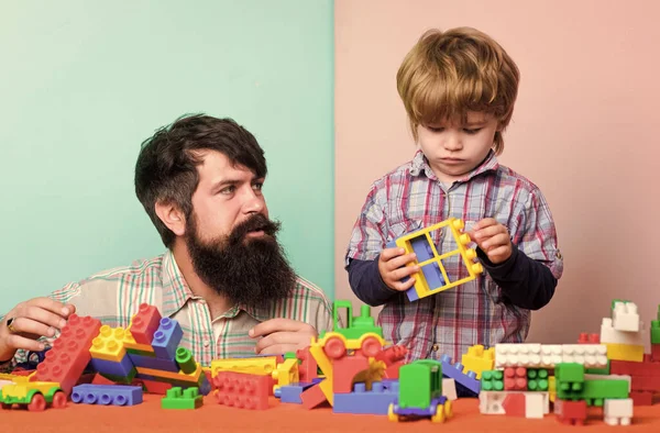 Father and son create colorful constructions with bricks. Bearded father and boy play together. Dad and kid build of plastic blocks. Useful toy. Child care development and upbringing. Father son game — Stock Photo, Image