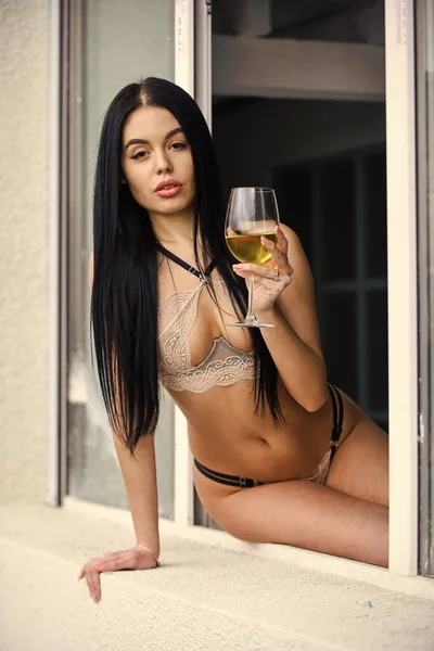 エンターテイメントのための渇き。ワインのグラスを持つ少女。エリートワイン。快楽主義の概念。家にいるのは楽しいかもしれない。セクシーな女の子のアルコールカクテル。ホットレディエロランジェリーはまだ窓に座る。女はワインを飲む — ストック写真
