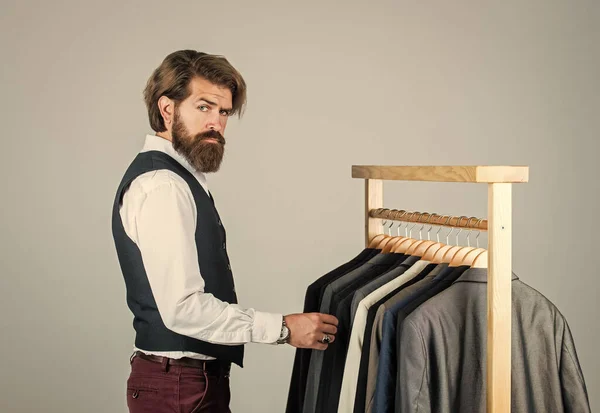 Man in custom tailored suit presenting expensive tailored tuxedo. Man in boutique. Man with suit. tailor in his workshop. Handsome bearded fashion man in classical costume suit. Tailor at work