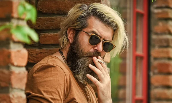 Snygg man med orakat ansikte. En mogen man som röker cigarett. Punk hipster man röker. Rökning och vana. begagnad eller passiv rök. brutal kaukasisk hane i glasögon. Man röker utomhus — Stockfoto