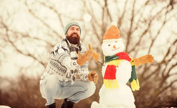 Ünnepeljünk! téli vakáció szabadtéren. meleg pulóver hideg időben. téli szezon tevékenység. Karácsony van. A szakállas ember hóembert épít. Az ember játszik a hóval. boldog hipster készen áll, hogy megünnepeljük a karácsonyt — Stock Fotó