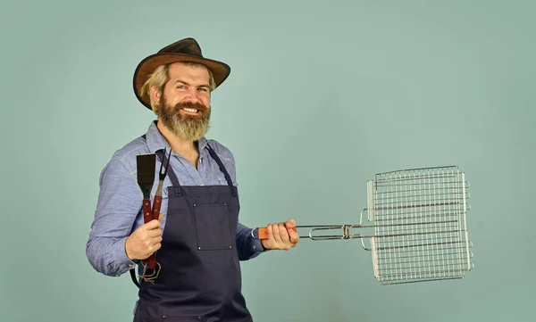 Culinair concept. Vrijgezellendag. Medium zeldzaam. Gereedschap dat vlees roostert. Man met schort houdt barbecue grill vast. Biefstuk koken. - Kookgerei. Boer met bbq apparatuur. Zomer picknick. Bbq Amerikaanse traditie — Stockfoto