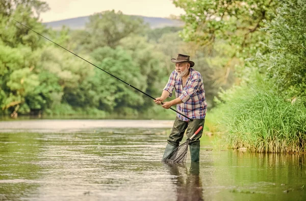 Fim de semana. Grande jogo de pesca. homem pesca com mosca. Homem a pescar peixe. hobby e atividade esportiva. Pothunter. pescador barbudo aposentado. Isca de truta. pescador com vara de pesca. Homens e peixes são iguais — Fotografia de Stock