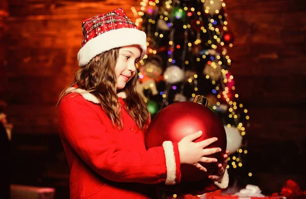 Me encanta decorar el árbol de Navidad. Ambiente festivo el día de Navidad. Chica traje de Santa Claus celebrar grandes adornos árbol de navidad bola. Decoraciones navideñas. Decora todo a tu alrededor. Juguete espumoso —  Fotos de Stock