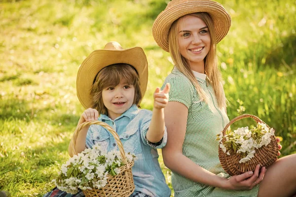 개념적으로요. 야생의 꽃들. 명절 잘 보내 세요. 엄마와 귀여운 아들은 빨대 모자를 쓰고 있다. 가족 농장. 야외의 아름다운 가족 환경 배경. 카우보이 가족 바구니에 꽃을 담고 있는 모습 — 스톡 사진