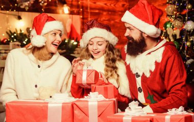 Harika bir hediye. Noel Baba şapkalı küçük bir çocuk ve ailesi. Mutlu noeller. Baba ve anne kızı sever. Mutlu aile yeni yılı kutluyor. Xmas hediye kutuları. Hediyeni aç. Kış tatili Alışveriş satışları