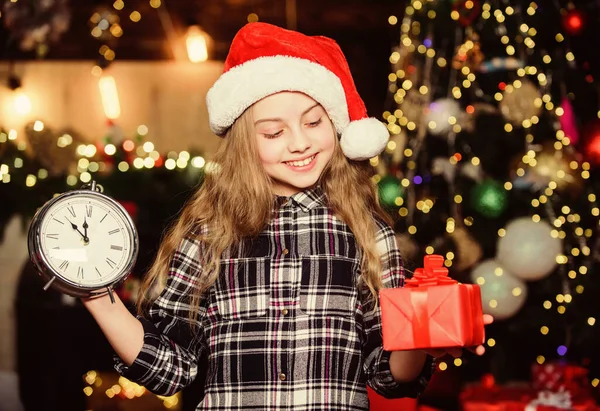 Lo que hay dentro. Niña con sombrero rojo. Regalo de vacaciones. Feliz año nuevo. Regalo para ti. Niña elfa. Árbol de Navidad. Regalo navideño. Santa Claus niña. Presente de compras. En Navidad. Caja de regalo —  Fotos de Stock