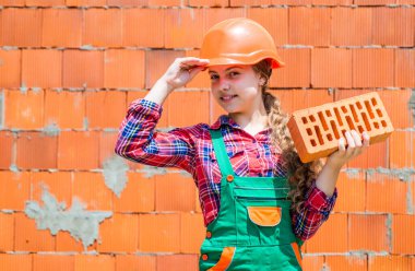 Kafasında tuğla olan mutlu çocuk mühendis, tuğla ustası