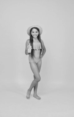 Havuz partisinde iyi eğlenceler. Mayolu küçük kız güneş kremini sunuyor. Deriyi güneşten korumak için losyon. Krem güneş yanığını önlüyor. pürüzsüz ve güzel güneş yanığı. yaz çocuk modası