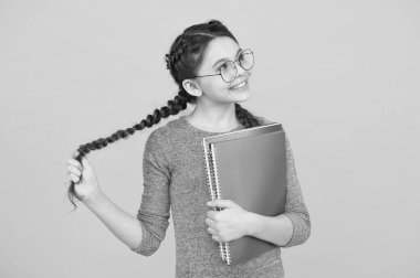 Hayal gücü uçuşu. Uzun örgülü kız kitapları tutuyor. Sarı arka planda düşünceli küçük hayalperest. Hayal gücü ve fantezi. Hayal gücünü geliştiriyor. Hayalgücü konularında öğrenmek