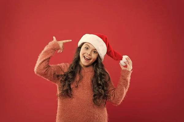 Bom humor. Tradições de inverno. Menina adorável com cabelos longos encaracolados usar Papai Noel chapéu fundo vermelho. A contar dias até ao Natal. Festa de Natal. Convite de Natal. Conceito de positividade — Fotografia de Stock