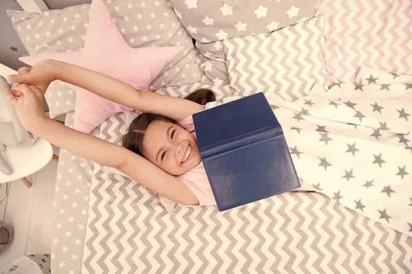 Oblíbená pohádka. Kniha o kouzelném milostném příběhu. Kéž by to byl pravdivý příběh. Dívka ležela v posteli a četla knihu. Příjemné chvíle v útulné ložnici. Dívka dítě dlouhé vlasy roztomilé pyžamo relaxovat a číst knihu — Stock fotografie