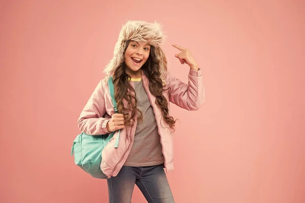 Escola de Qualidade. pequena menina feliz de volta para a escola. férias de inverno. criança roupas quentes fundo rosa. chapéu earflap criança feliz. estudante com saco ir para casa. Fim do ano lectivo. Não há mais exames. — Fotografia de Stock