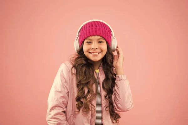 En lycklig liten flicka lever ett rosa liv. Rosa är hennes favoritfärg. Liten unge lyssna musik headset. barnlångt lockigt hår. hårvård under vintersäsongen. varma kläder för kallt väder. semestertid — Stockfoto