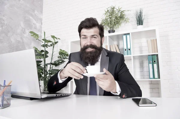 Diskutujte o obchodu s kávou. Muž pohledný šéf sedí v kanceláři a pije kávu. Pohodlný pracovní prostor. Vousatý obchodník formální oblek relaxující s kávou. Kancelářské životní návyky. Opravdu dobré cappuccino — Stock fotografie