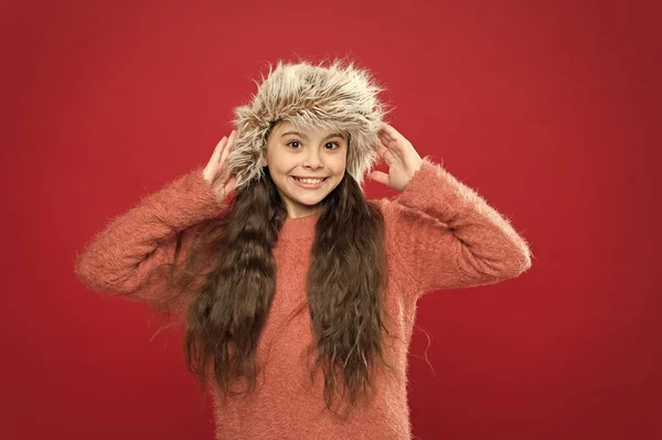 Piccola ragazza carina in stile invernale muro rosso. attività di vacanza all'aperto. bambino piccolo pronto per l'inverno. assistenza sanitaria stagionale. alla moda bambino. Vestiti caldi e consigli accessori. felice bambina in cappello auricolare — Foto Stock