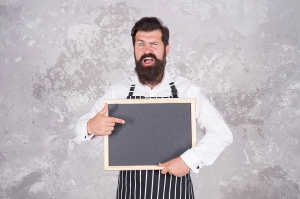 Cocinero masculino hipster caucásico con la cara sorprendida señalando el dedo en pizarra vacía publicidad clase magistral escuela culinaria, el mejor precio —  Fotos de Stock