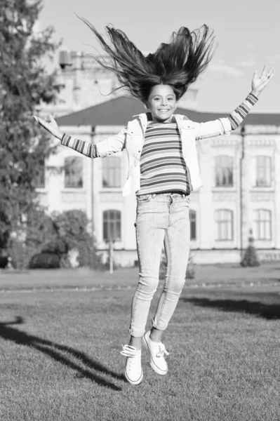 Zorgeloos zijn. vol energie. activiteiten voor kinderen. gelukkig kind springen en voel je vrij. Kindergeluk. klein meisje met krullend haar springen buiten. Voorjaarsfeest. kind vliegen in beweging — Stockfoto