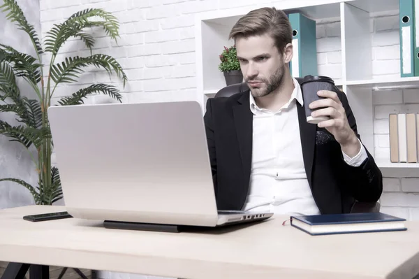 Un bell'uomo in ufficio. Ispirato con una tazza di caffè fresco. Avviare un'attivita '. Concetto di amministratore delegato. Sviluppo del business. Uomo d'affari che beve caffe '. L'uomo sicuro usa il computer portatile — Foto Stock