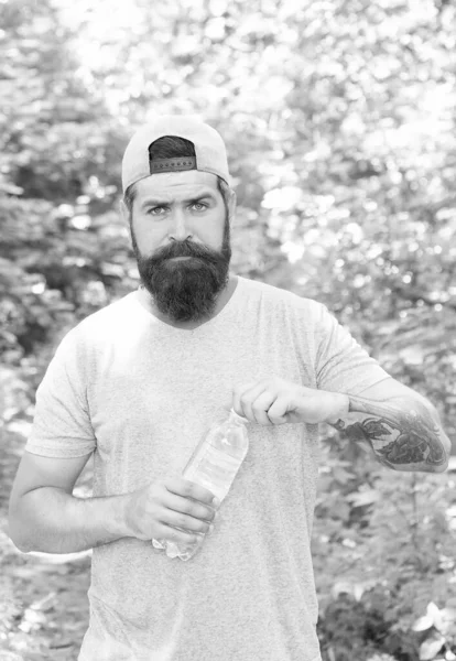 Neem een slok. Mannen hebben dorst. brutale hipster in het bos. nieuwe plaatsen ontdekken. Tijd voor de picknick. Een man met een snor drinkt water. Een volwassen man met een baard en pet. zomervakantie. man hipster wandelen — Stockfoto