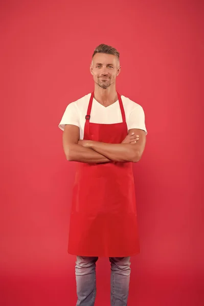 Gastvrije en zelfverzekerde echtgenoot. Man in schort in de keuken. Knappe conciërge draagt uniform voor schoonmaak. vriendelijke lachende barman. Professionele reiniging. Huishoudelijk en menselijk concept — Stockfoto