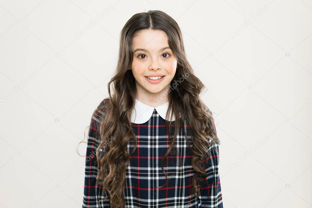 Child long curly hair. Happy schoolgirl stylish uniform. Happy childhood concept. Happy smiling cheerful kid portrait. Emotions emotional expression. Enjoy perfect hair. Small girl nice hairstyle