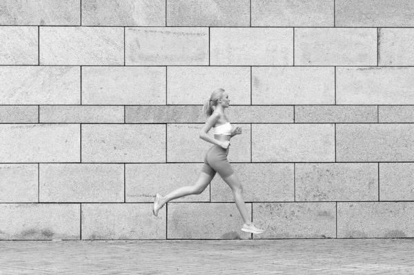 Ο αθλητισμός λέει να προχωράμε μπροστά. Σέξι αθλήτρια τρέχει έξω. Απολαμβάνω αθλητικές δραστηριότητες. Σωματική εκπαίδευση και άθληση. Αθλητισμός και φυσική κατάσταση. Κατάστημα αθλητικών ειδών. Το τρέξιμο είναι η θεραπεία μου — Φωτογραφία Αρχείου
