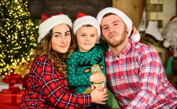 Kerstfeest. Vrolijk kerstfeest. Mama, papa en kleine kinderen hebben plezier op het feest. Gelukkig gezin viert nieuwjaar. Ouders met zoon dragen kerstmuts. vader en moeder met kind blijven thuis op vakantie — Stockfoto