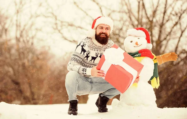 クリスマス休暇だ。屋外でプレゼントを。Xmasの準備ができて幸せなヒップスター。髭の男が雪だるまを作る。新年明けましておめでとう。冬休みだ。寒い日の暖かいセーター。冬の季節。メリークリスマス — ストック写真