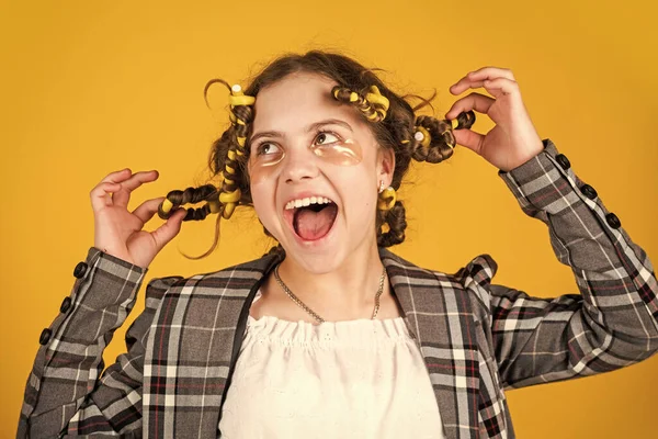 Dívka s natáčkami a sponkami do vlasů na žlutém pozadí. Holčička si kudrlinky kolem vlasů. Vytvořit krásný účes. Nádherný účes. Šťastné dítě. Kadeřnický salón. Dokonalá krása — Stock fotografie