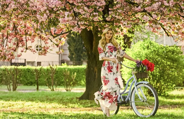 Glücklicher Frühlingstag. junges modisches Mädchen mit Retro-Fahrrad in der Nähe von Kirschblüten. Mädchen mit Oldtimer-Fahrrad in rosa Sakura-Gasse. blühender Baum im Frühling. natürliche weibliche Schönheit. Frau im Garten — Stockfoto
