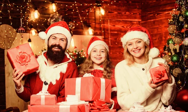 クリスマスを祝う家族と父サンタクラスの衣装。サンタの帽子をかぶった両親を持つ素敵な娘。サンタからの贈り物。最も近い人々の世話をする。団結の概念。愛と優しさ — ストック写真