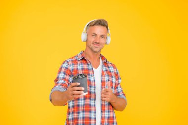 Mutlu modern adam, kahve fincanının reklamını ve sarı arka planının reklamını yapıyor.