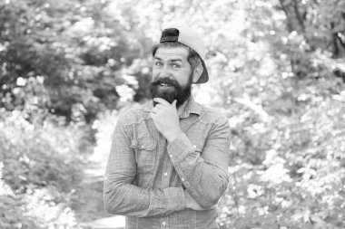 Dışarıyı düşün. Sakallı adam gündelik tarzda. Kamp yapmaya hazırım. Erkek mutlu turist şapkası takıyor. Spor ve spor kıyafetleri. Kendine güvenen ve yakışıklı vahşi bir adam. Bıyıklı, vahşi, beyaz bir hippi.