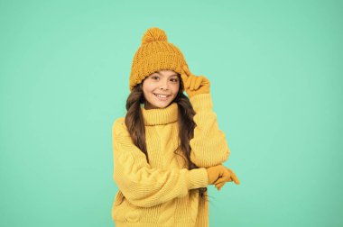 Çok şık. Şapka ve eldivenler aksesuar. Mutlu çocuk turkuaz duvar. Grip yok. Kış için hazırlan. Kış tatili Ev yapımı örgü. Soğuk sezon modası. Kendini sıcak tut. Küçük kız en sevdiği kazak