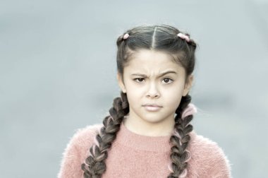 Yanlış olan ne? Şaşkın bakışlı küçük bir çocuk. Küçük çocuk uzun esmer örgüler takıyor. Sıradan moda tarzında sevimli bir çocuk. Dışarıdaki sevimli kız çocuğu. Çocukluk. Uluslararası Çocuk Günü