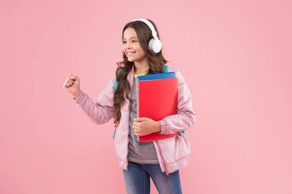 快乐精力充沛的学童听着耳机里播放的音乐，粉色背景的，solfeggio — 图库照片