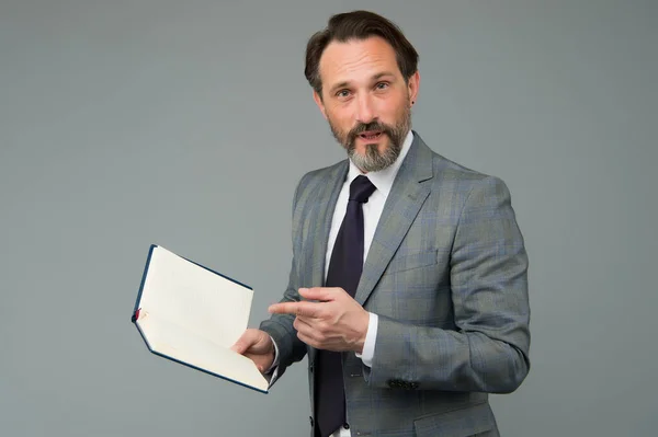 Get more knowledge. Bearded man point finger at open book. School teacher grey background. Making report. Presenting paper. Formal fashion style. Every book available here, copy space — ストック写真