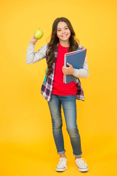 Happy school kind houden boeken en natuurlijke appel fruit gele achtergrond, tandheelkundige gezondheid — Stockfoto