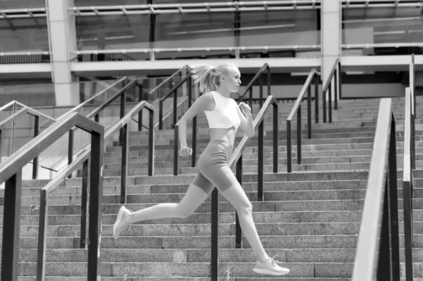 Corri come una bestia, fai bella figura. Una donna energica corre allo stadio. Corri veloce. Atleta in abbigliamento sportivo sexy. Corridore atletica femminile. Allenamento e allenamento. Fitness e motivazione sportiva. Corri ancora. — Foto Stock