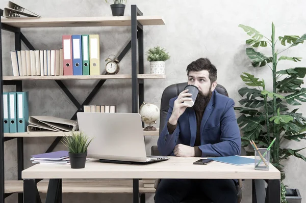 Schläfriger halbwach bärtiger Hipster in Formalbekleidung trinkt Kaffee zum Mitnehmen am Arbeitsplatz, Koffein — Stockfoto